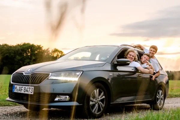 Drei Fundraiser schauen grinsend aus dem Auto