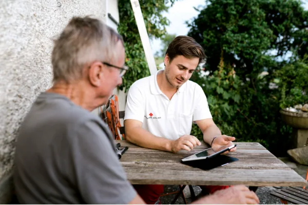 Ein Fundraiser sitzt mit einem Bürger am Tablet