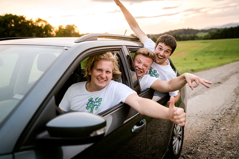 Drei Fundraiser winken fröhlich aus dem Auto auf dem Weg zum Einsatz